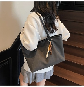 Detail of dark grey canvas tote bag with wooden bead charm and black shoulder strap