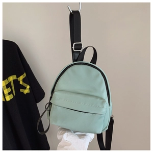 Detail of mint green nylon mini backpack showing hidden zipper pocket and metal buckle