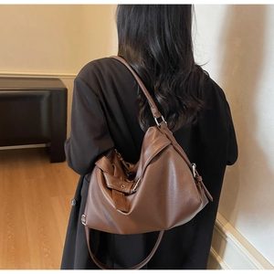 Detailed close-up of dark brown leather tote bag showing lychee grain texture and metal buckle