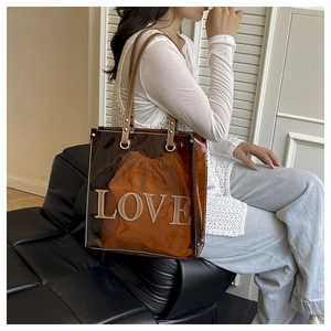 Detailansicht der braunen transparenten PVC-Tasche mit orangefarbenem Beutel und LOVE-Stickerei