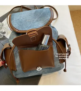 Detail of blue denim and brown leather backpack with front pocket and magnetic closure