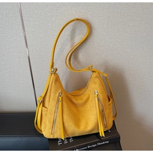 Detailed macro view of ginger yellow suede crossbody bag with dual vertical zipper tassels