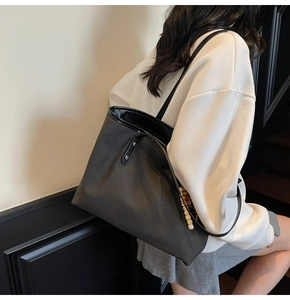 Detail of dark gray tote bag featuring charcoal texture, black trim and wooden bead charm