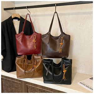 Detail of multi-color tote bags in burgundy and black with ethnic tassel charms