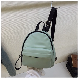 Detail of light green waterproof nylon backpack showing adjustable black straps and zippers