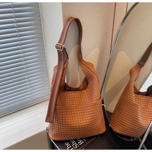 Détail d'un sac seau en cuir tressé marron avec bandoulière réglable et boucle dorée