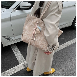 Detail der beige Blumentasche mit eleganten Mustern und dekorativen Anhängern