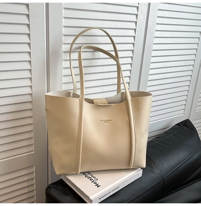 Dettaglio borsa shopper beige con logo BAIGILANNIANBAG su divano in pelle nera