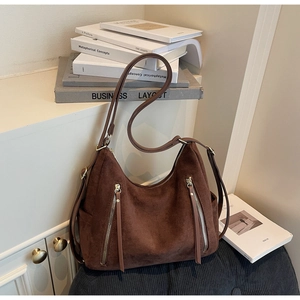 Detailed close-up of dark brown suede hobo bag with parallel silver zippers and tassels