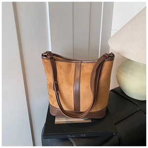 Detail of vintage matte suede bucket bag with contrast brown leather trim and shoulder strap