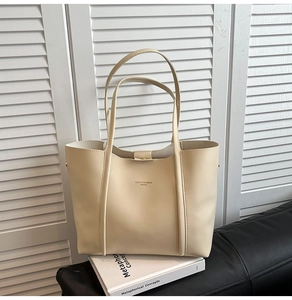 Dettaglio borsa tote in pelle bianco crema con cuciture verticali e logo dorato
