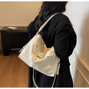 Detailed view of white lychee leather tote bag with black buckles on a shoulder model