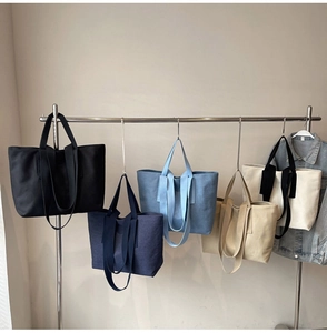 Row of large canvas tote bags in black, navy, blue, and beige on a display rack