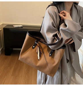 Detail view of large brown suede tote bag with beaded tassels and leather trim