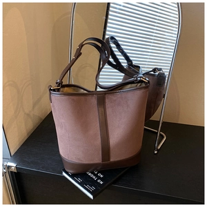 Detail of vintage brown suede bucket bag featuring leather trim and a slim shoulder strap