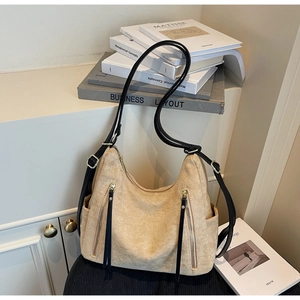 Detail of beige faux suede tote bag featuring parallel zippers and slender black straps
