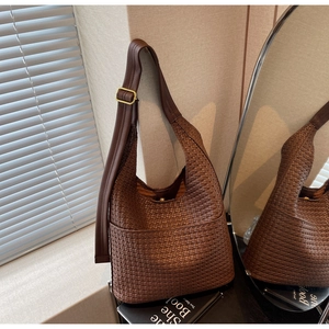 Détail d'un sac seau en cuir tressé marron foncé avec bandoulière et boucles dorées