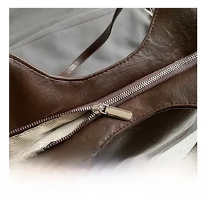Detail shot of a dark brown leather tote bag showing a silver metal zipper and chevron lining