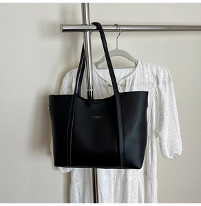 Borsa tote classica in pelle nera opaca con logo dorato mostrata in un set appeso