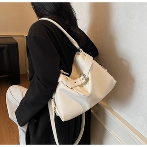 Detail of cream white pebbled leather tote bag with wide strap and metallic buckle design