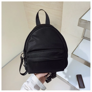 Close-up of lightweight black mini nylon backpack showing front pocket and zip detail