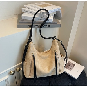 Detail of beige faux suede tote with metallic zippers and adjustable black leather strap
