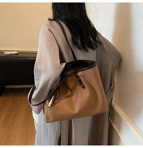 Brown canvas tote bag detail featuring dark leather straps and wooden bead accessories
