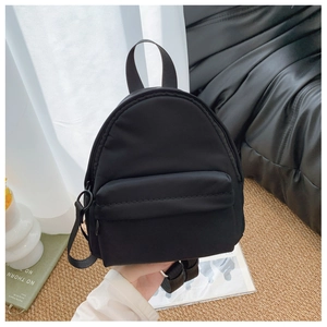 Detail of a black nylon mini backpack featuring a smooth texture and zippered front pocket
