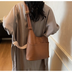 Détail du sac à bandoulière en cuir tressé avec sangle réglable et boucle dorée