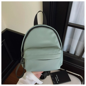 Detail of mint green mini backpack showing the zipper pocket and nylon texture
