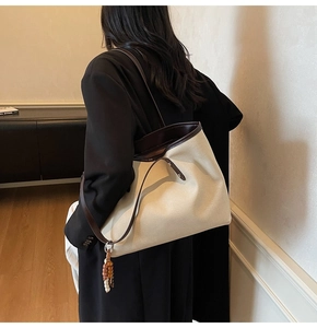 Detailed back view of a minimalist canvas tote bag with brown leather trim on a model