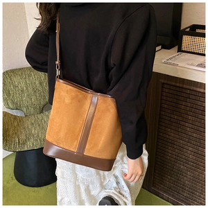 Detail view of a vintage tan suede bucket bag with dark brown leather trim and strap