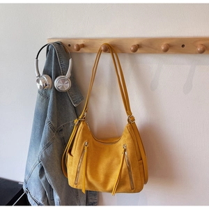 Close-up of mustard yellow faux suede tote bag with dual front zippers on wooden hanger