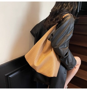 Detail of light brown woven leather tote bag showing large capacity and weave texture