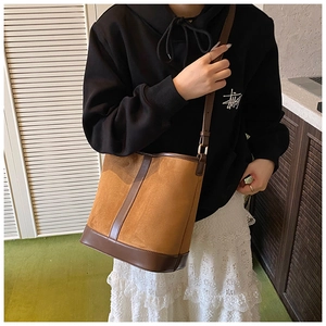 Close-up of caramel suede bucket bag with leather trim on model showing large capacity