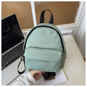 Close-up of a mint green mini nylon backpack with black straps and zip pocket