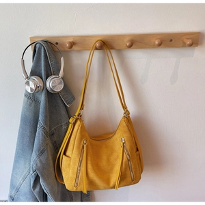Yellow suede tote bag with dual zipper detail hanging in a lifestyle scene with denim
