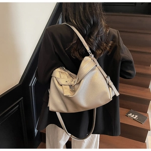 Detail of champagne gold tote bag with lychee texture and silver buckle on crossbody strap