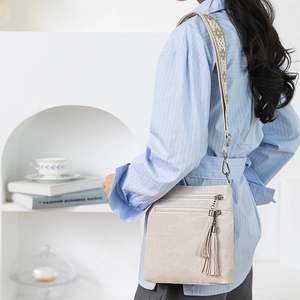 Detail of cream crossbody bag featuring triple zippers and ethnic jacquard wide strap