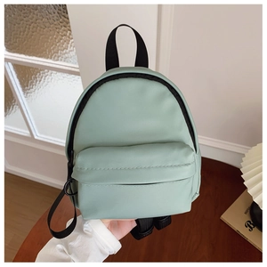 Detail of mint green mini backpack with black zipper and textured synthetic leather