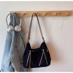 Detail of black vintage tote bag with decorative zippers and brown leather handles