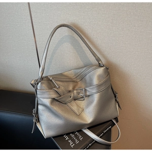 Macro detail of silver pebbled leather texture and buckle strap on a modern tote bag