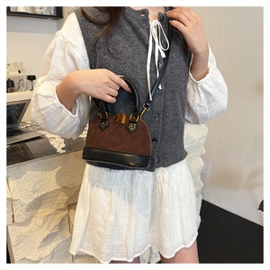 Détail d'un sac coquille vintage bicolore en daim marron et cuir lisse noir élégant