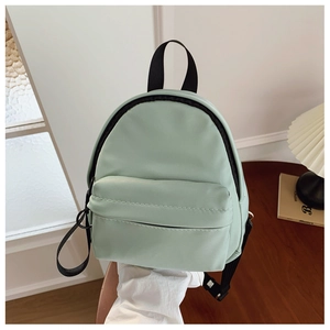 Close-up of mint green mini backpack with front zipper pocket on a wooden table
