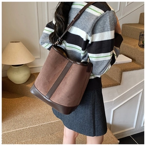 Close-up of brown suede and smooth leather bucket bag featuring adjustable strap details