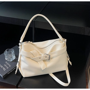 Detailed close-up of cream pebble grain leather texture and strap buckle on a tote bag
