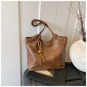 Detailed view of a vintage brown tote bag with stylish wooden bead and tassel keychain charm