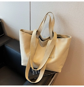 Detail view of large canvas tote bag with double shoulder straps on leather sofa
