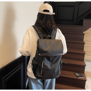 Detailed back view of a black large capacity nylon backpack on a casual model for commuting