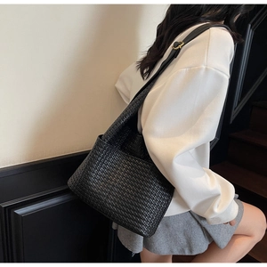 Détail d'un sac bandoulière en cuir tressé noir avec bandoulière réglable sur modèle